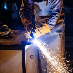 Worker cutting metal with plasma equipment on plant.